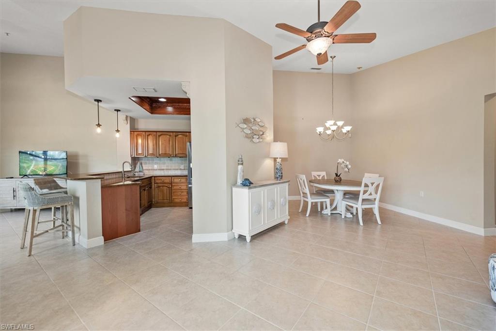 8375 Whisper Trace Way, Unit M203 Naples, FL 34114 - Photo 10 of 36 a living room with furniture a dining table and a chandelier