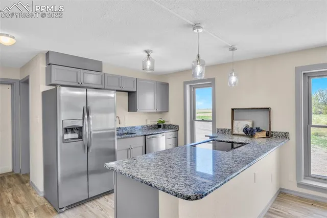 a kitchen with granite countertop a counter space cabinets stainless steel appliances and a window