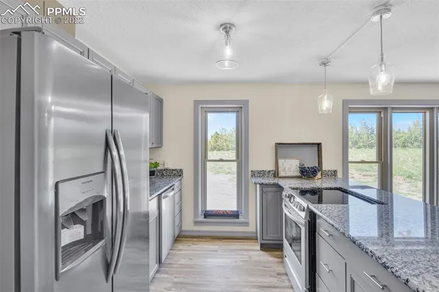 a kitchen with kitchen island granite countertop a refrigerator a sink a stove and a wooden floors