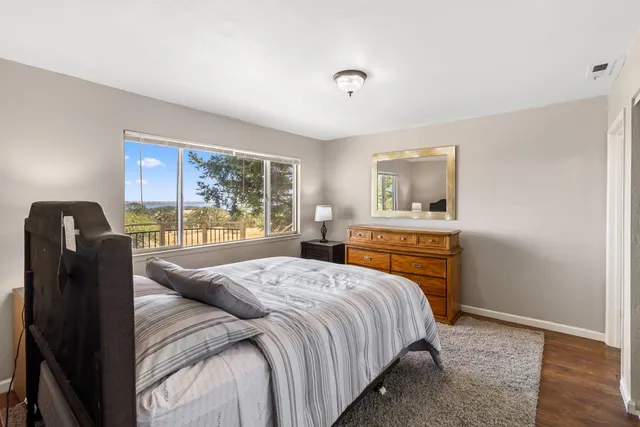 a bedroom with a bed and dresser with wooden floor