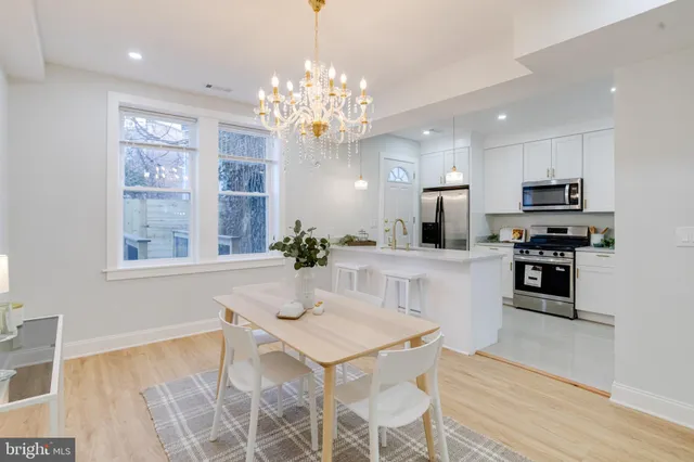 a kitchen that has a lot of white cabinets and stainless steel appliances