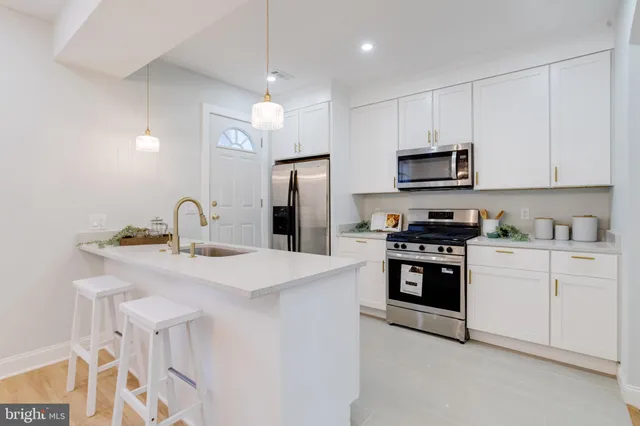 a kitchen with stainless steel appliances a sink a stove a refrigerator cabinets and a window