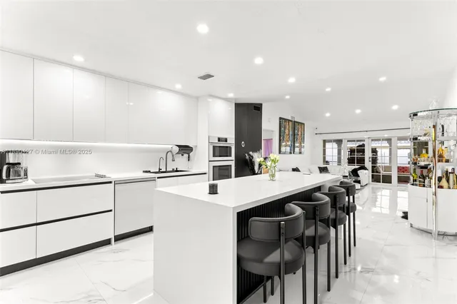 a kitchen with stainless steel appliances kitchen island granite countertop a table chairs and a refrigerator