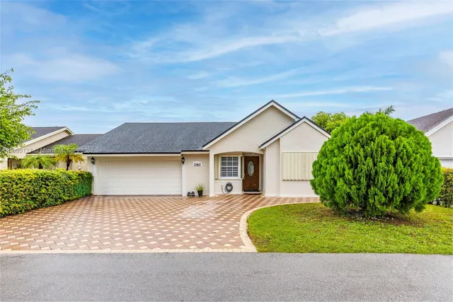 a view of a house with a yard plants and large tree