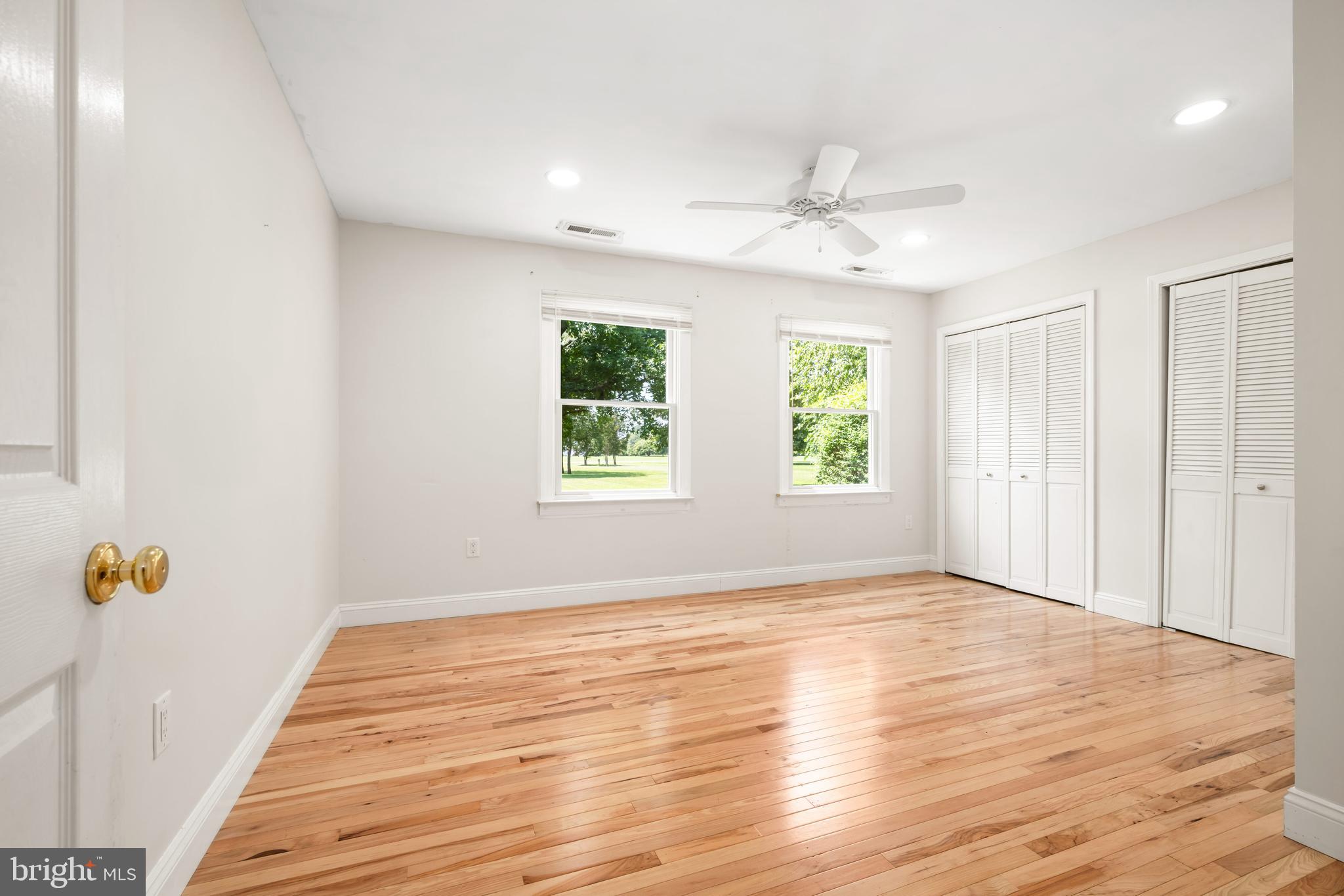 26648 Arcadia Shores Road Easton, MD 21601 - Photo 15 of 25 an empty room with wooden floor chandelier fan and windows