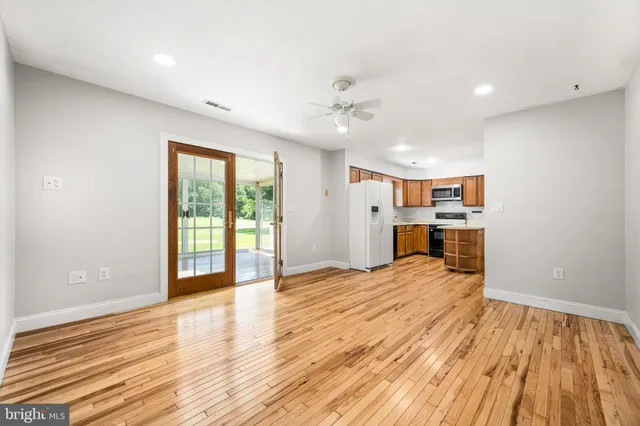 a view of empty room with wooden floor and fan