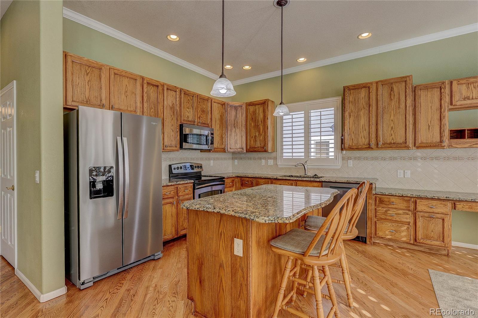 10292 South Nickolas Avenue Highlands Ranch, CO 80124 - Photo 2 of 46 a kitchen with stainless steel appliances granite countertop wooden cabinets a refrigerator a sink a stove a microwave and island