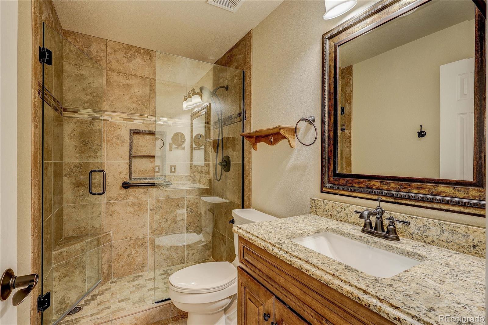 10292 South Nickolas Avenue Highlands Ranch, CO 80124 - Photo 26 of 46 a bathroom with a granite countertop sink a mirror a toilet and shower