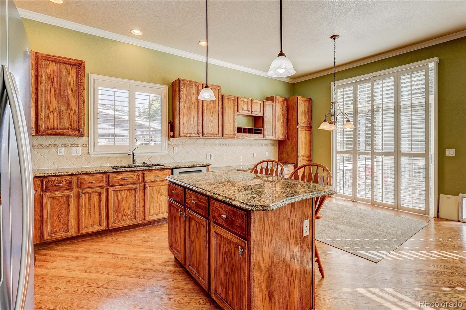 10292 South Nickolas Avenue Highlands Ranch, CO 80124 - Photo 3 of 46 a kitchen with stainless steel appliances granite countertop a sink a counter space and wooden floor