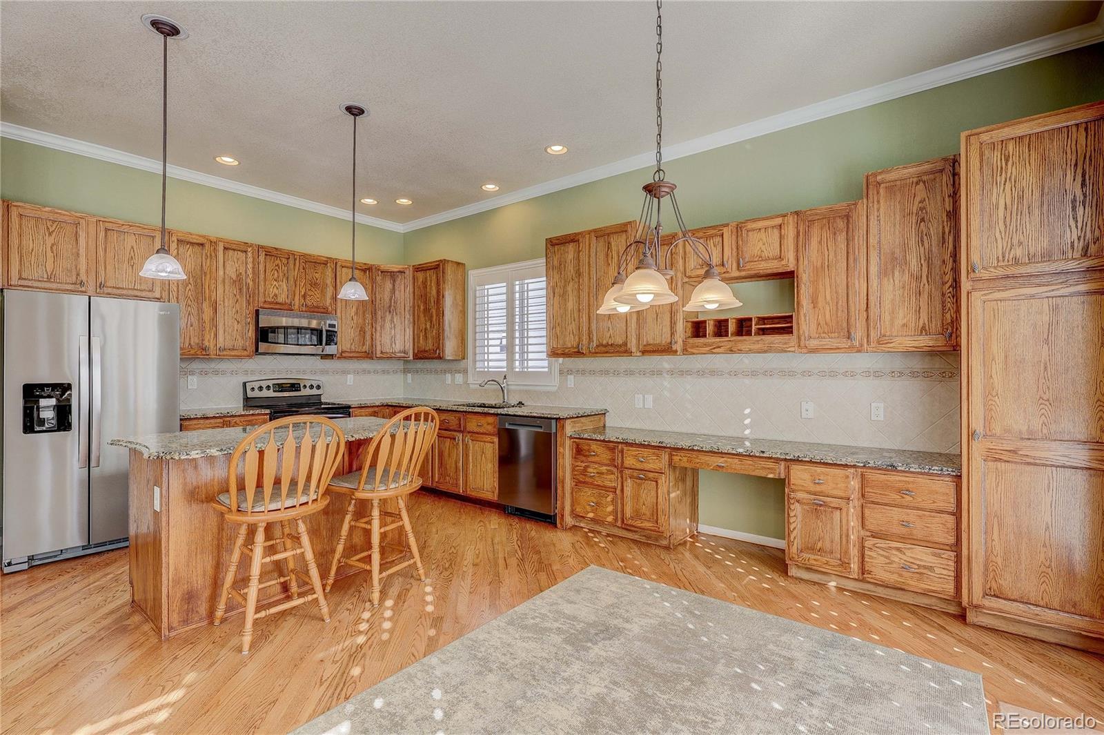 10292 South Nickolas Avenue Highlands Ranch, CO 80124 - Photo 6 of 46 a kitchen with stainless steel appliances granite countertop a refrigerator a oven a sink a dining table and chairs with wooden floor