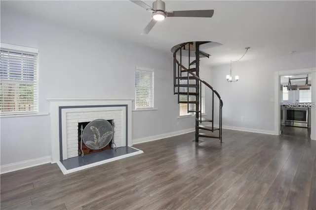 a view of an empty room with wooden floor fireplace and a window