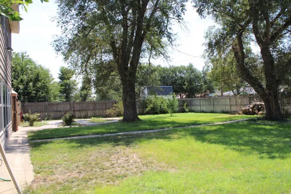 a backyard of a house with swimming pool and large trees