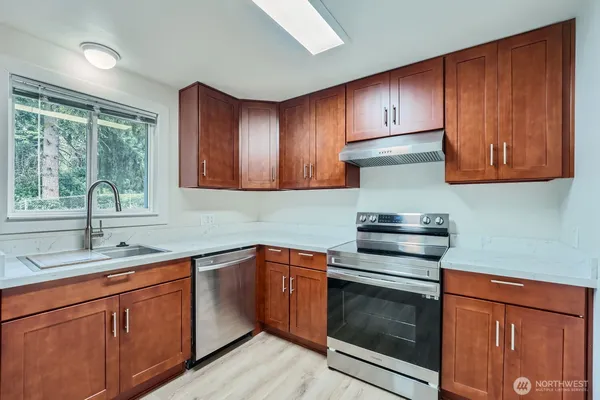 a kitchen with stainless steel appliances granite countertop wooden cabinets granite counter tops and a window