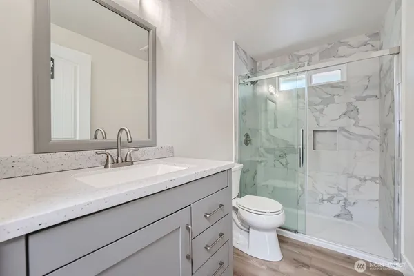 a bathroom with a granite countertop sink a toilet and shower