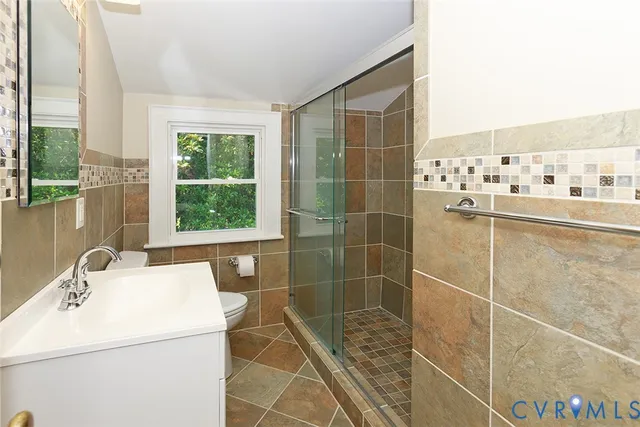 a view of an empty room with wooden floor and a ceiling fan