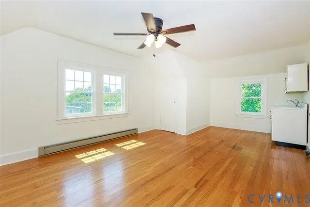 a view of empty room with wooden floor and ceiling fan