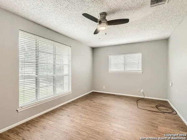 a view of an empty room with a window and wooden floor