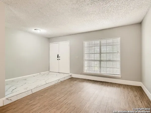 an empty room with wooden floor and windows