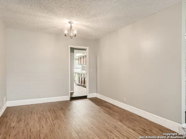 an empty room with wooden floor chandelier and windows