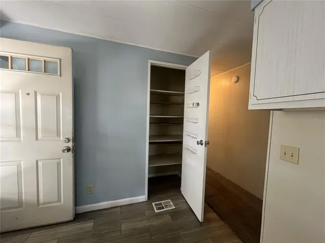 a view of an empty room with wooden floor and closet