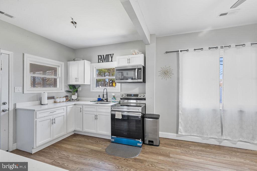 8489 Arbutus Road Pasadena, MD 21122 - Photo 12 of 41 a kitchen with stainless steel appliances a sink cabinets and wooden floor