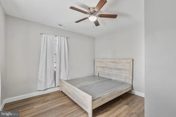 an empty room with wooden floor and ceiling fan