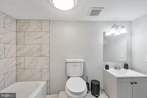 a bathroom with a toilet a sink a mirror and bathtub