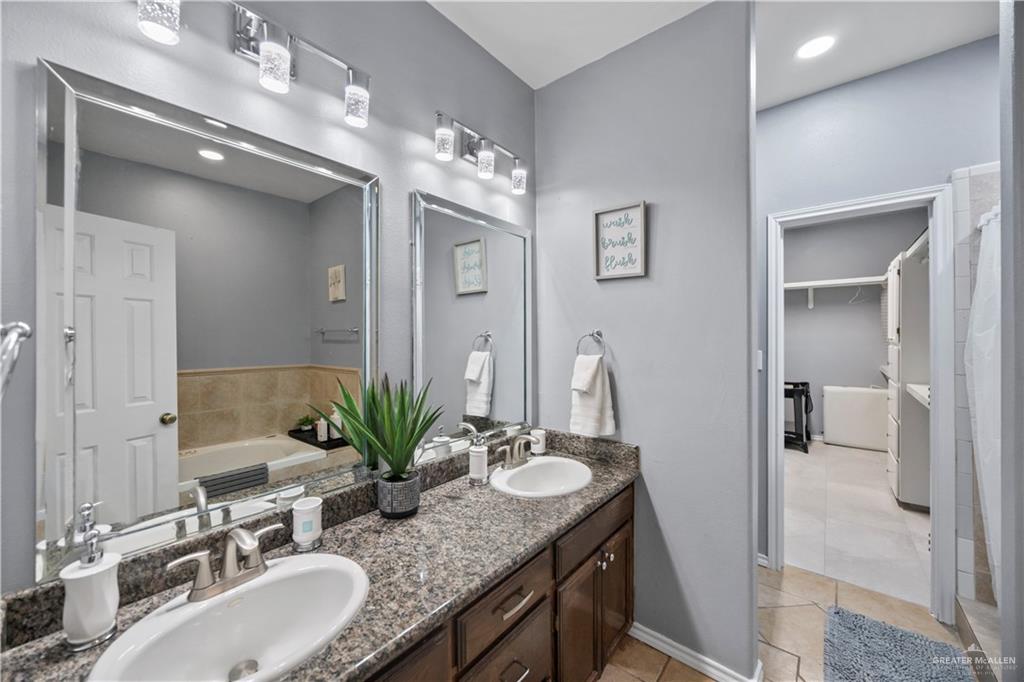 3107 South 6th Lane McAllen, TX 78503 - Photo 18 of 31 a bathroom with a granite countertop sink a large mirror and a shower