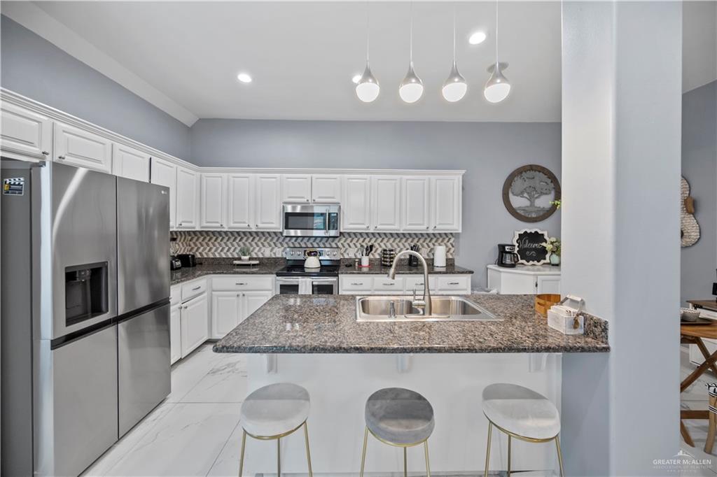 3107 South 6th Lane McAllen, TX 78503 - Photo 9 of 31 a kitchen with granite countertop stainless steel appliances a stove refrigerator sink and cabinets