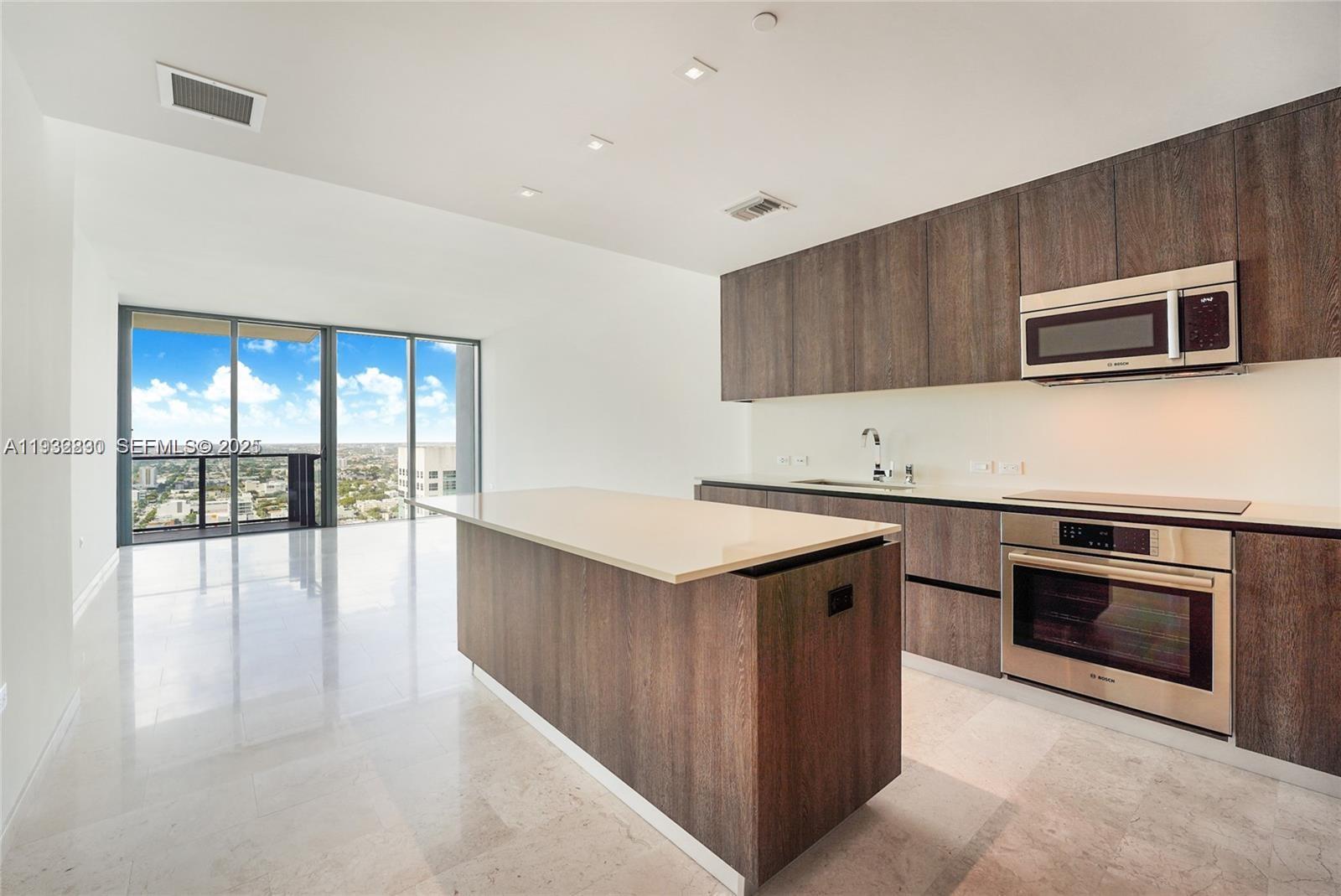 88 Southwest 7th Street, Unit 2708 Miami, FL 33130 - Photo 3 of 12 a kitchen with stainless steel appliances kitchen island a stove sink and microwave
