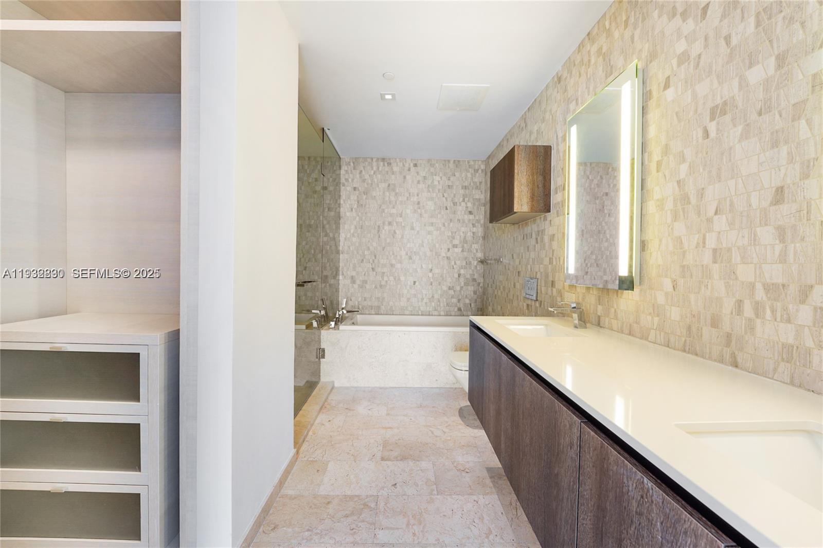 88 Southwest 7th Street, Unit 2708 Miami, FL 33130 - Photo 9 of 12 a bathroom with a double vanity sink a mirror and a bathtub