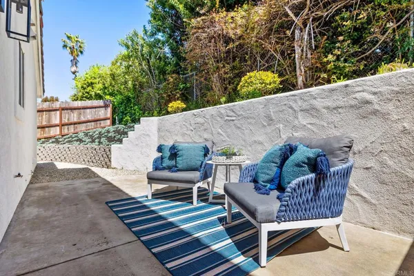 a balcony with table and chairs and potted plants