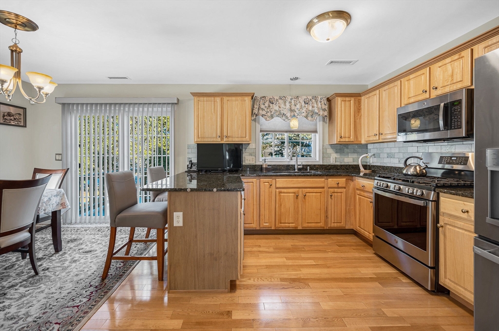 262 Littleton Road, Unit 14 Chelmsford, MA 01824 - Photo 11 of 30 a kitchen with stainless steel appliances granite countertop a stove top oven a sink dishwasher a dining table and chairs with wooden floor