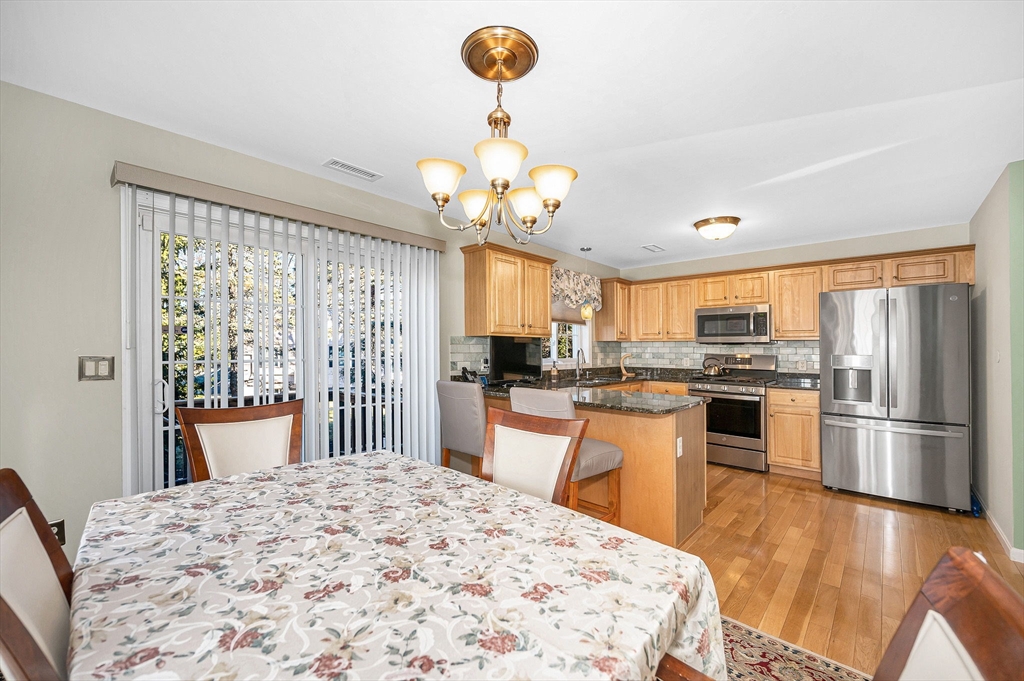 262 Littleton Road, Unit 14 Chelmsford, MA 01824 - Photo 15 of 30 a kitchen with stainless steel appliances kitchen island granite countertop a refrigerator a stove top oven a sink dishwasher and a dining table with wooden floor