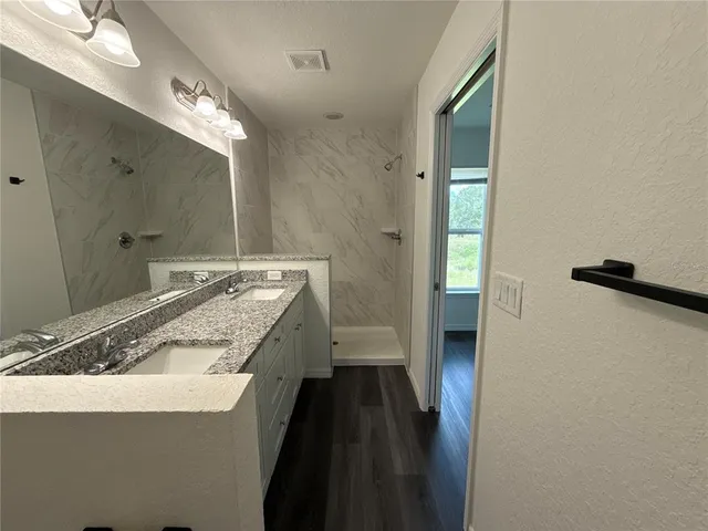 a bathroom with a granite countertop sink a toilet and shower