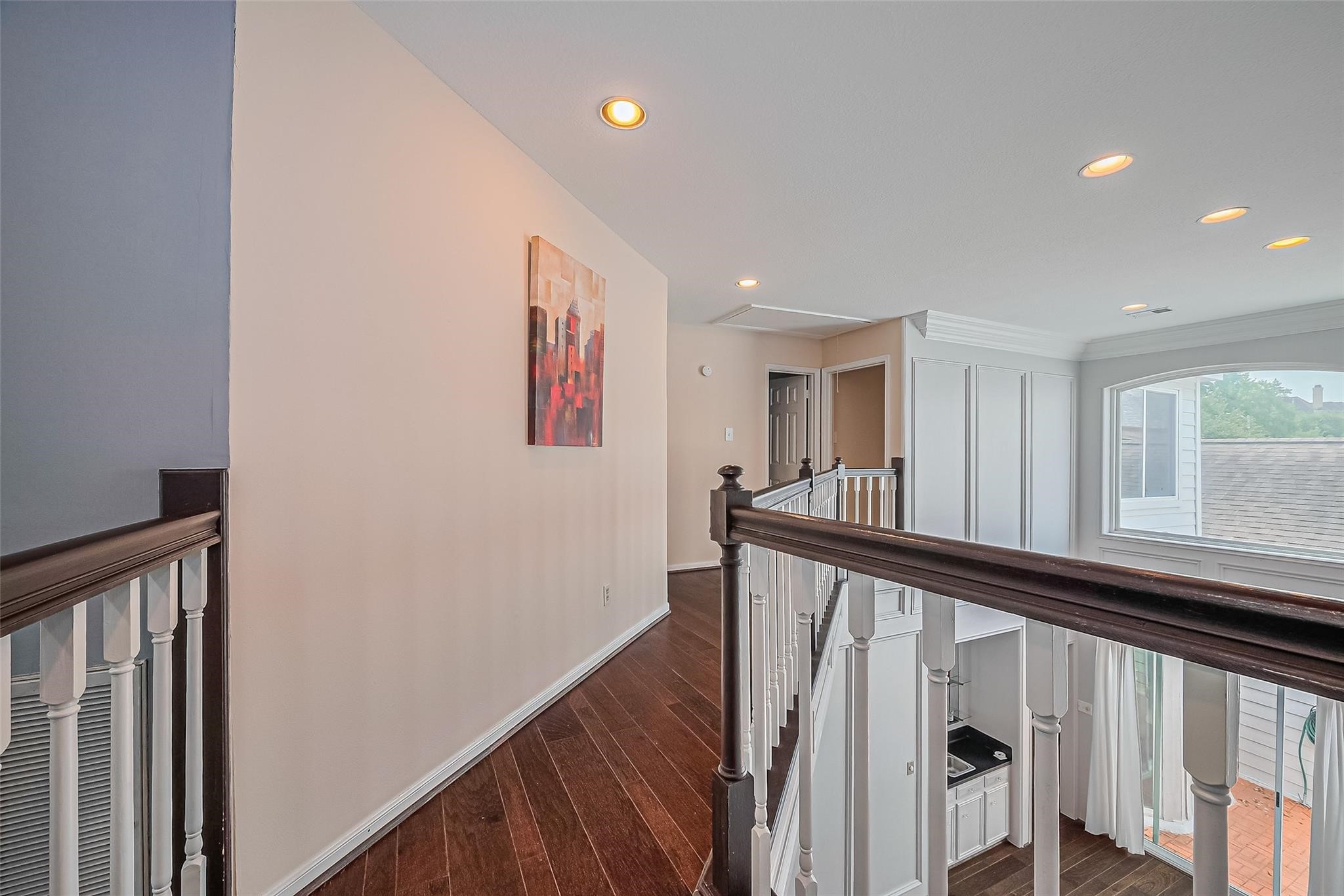 4305 Westheimer Road Houston, TX 77027 - Photo 15 of 25 Bright and inviting upper hallway with elegant wood flooring, recessed lighting, and a large window offering natural light and views.