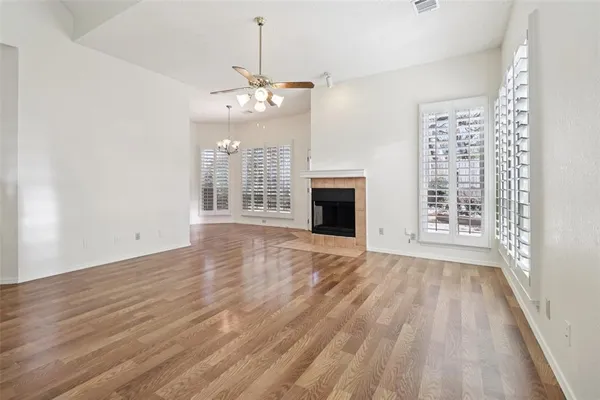 a view of an empty room with wooden floor fireplace and a window