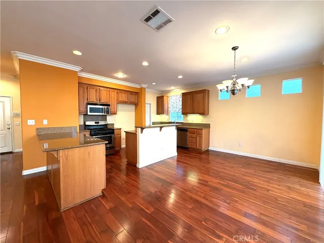 a open kitchen with kitchen island a stove a sink cabinets and wooden floor