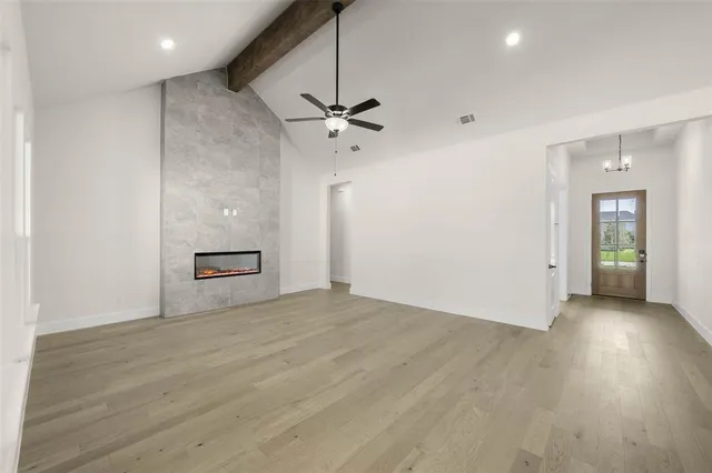 an empty room with wooden floor ceiling fan and windows