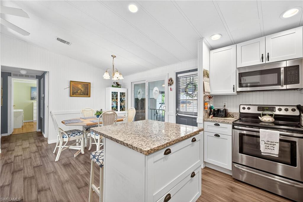 170 Oceans Boulevard, Unit 170 Naples, FL 34104 - Photo 9 of 36 a open kitchen with stainless steel appliances granite countertop a stove top oven a sink dishwasher a dining table and chairs with wooden floor