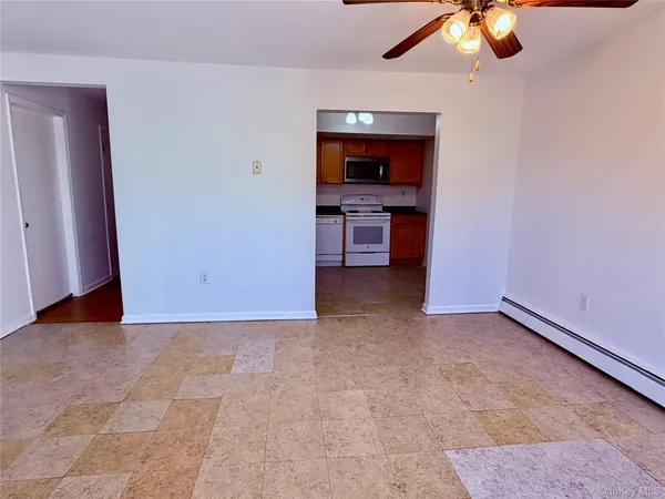 an empty room with a flat screen tv and kitchen view