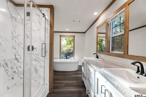 a bathroom with a sink a large mirror and a bathtub next to a window