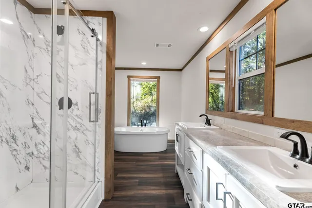 a bathroom with a sink a large mirror and a bathtub next to a window