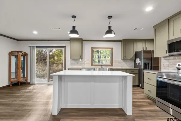 a kitchen with stainless steel appliances granite countertop a stove top oven a refrigerator a sink and dishwasher with wooden floor