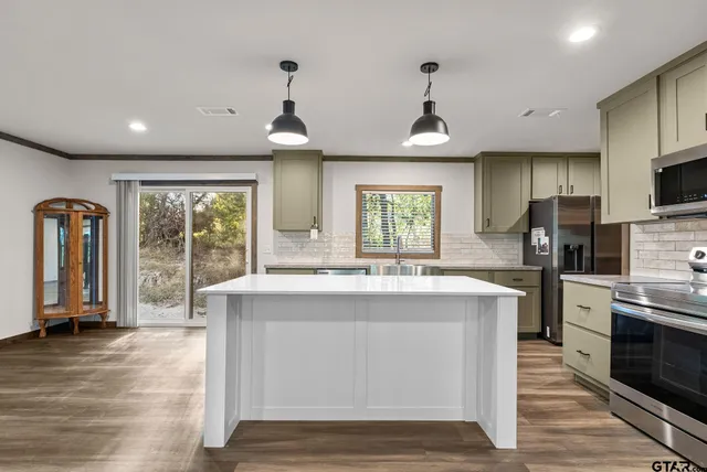 a kitchen with stainless steel appliances granite countertop a stove top oven a refrigerator a sink and dishwasher with wooden floor