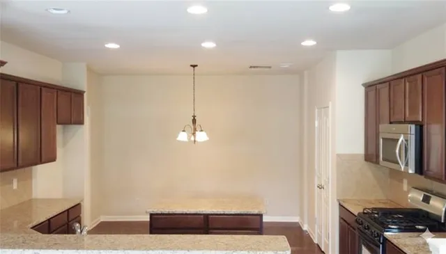 a kitchen with stainless steel appliances granite countertop a refrigerator a sink and a stove