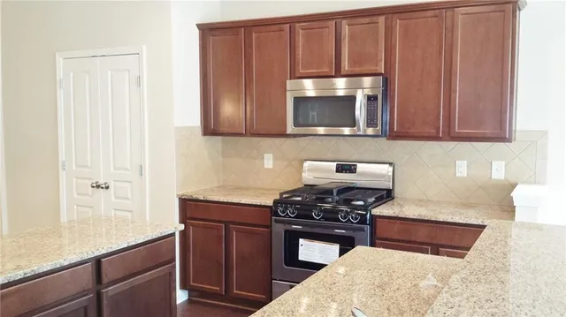 a kitchen with granite countertop a stove and a microwave