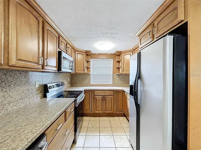 a kitchen with stainless steel appliances granite countertop a refrigerator a sink and wooden cabinets