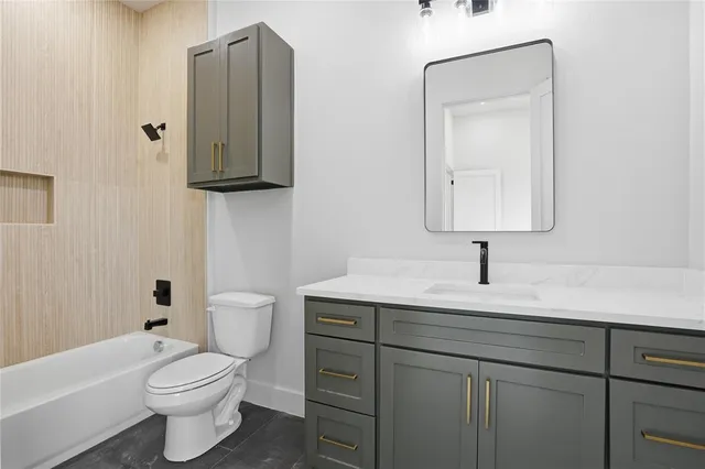 a bathroom with a toilet sink vanity tub and mirror