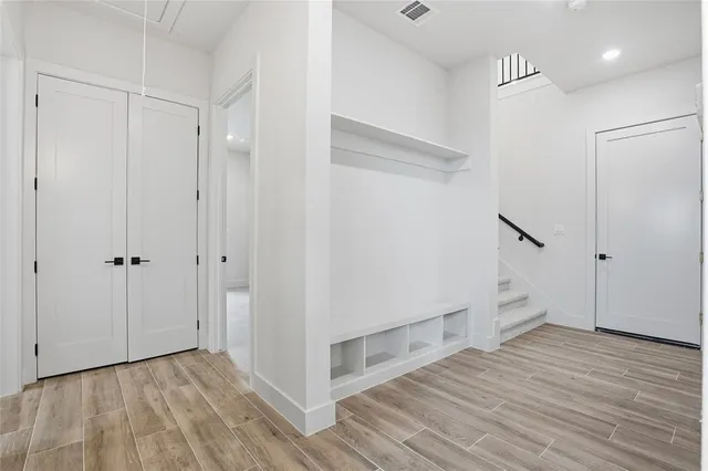 a view of an empty room with wooden floor and a hallway